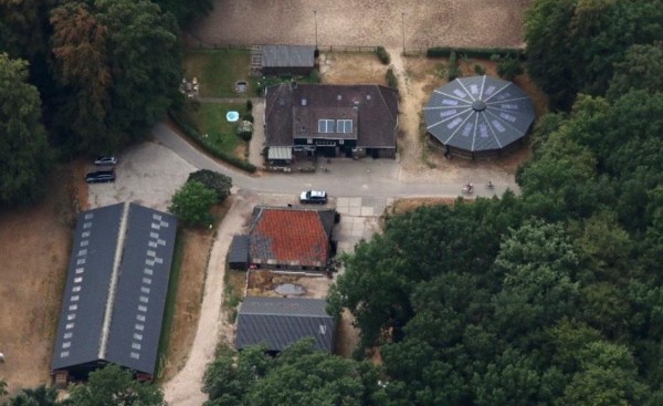 Luchtfoto van de Enkhoeve met stallen, erf en overkapping tussen de bossen